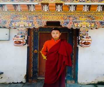 A monk from Bhutan with his head shaved wearing a distinct maroon robe